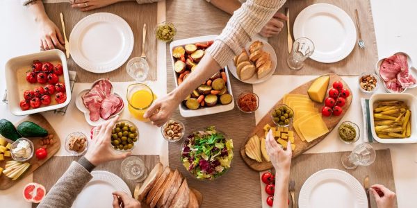 Overhead view of a diverse cheese platter setup for a delicious meal, featuring fresh produce and juices on a table.